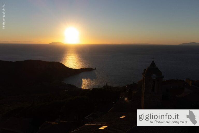 Veduta aerea con il drone del campanile di giglio castello al tramonto con vista sulla baia del Campese e Montecristo