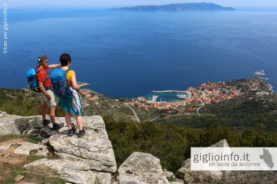 Due persone durante il trekking all'Isola del Giglio con vista Panoramica su Giglio Porto e il Monte Argentario